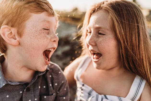 Side view of young freckled redhead siblings laughing at each other United States, California, Coronado CR_KESM190930-198476-01