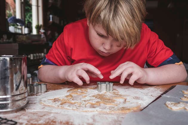 Front view of boy cutting out gingerbread from dough New Zealand, Taranaki, Hawera CR_LVBS191016-207965-01