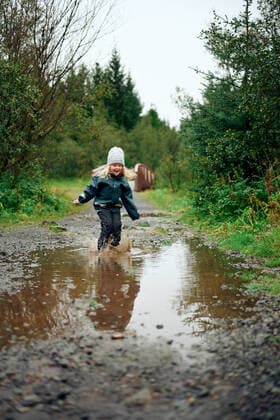 Girl standing in puddle and making spray in forest Ellidaardalur, Reykjavik, Iceland CR_OSBJ191028A-214813-01