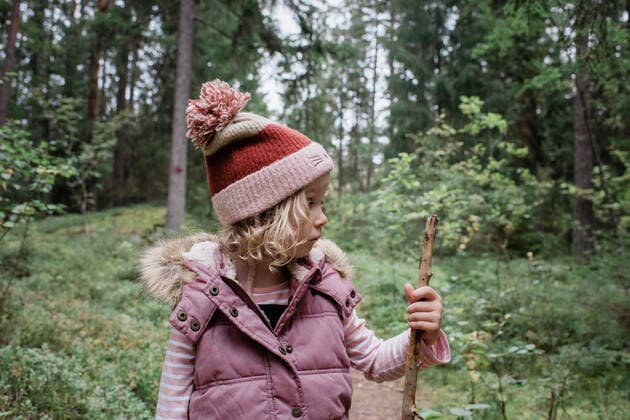 young girl stood in a forest looking at her walking stick thinking Sweden, Stockholm County, Norrtälje CR_RABE191001A-200287-01