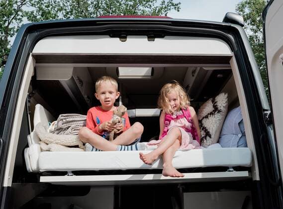 brother and sister sat on a bed in a camper van on vacation in summer Sweden, Stockholm County, Norrtälje CR_RABE191011-182167-01