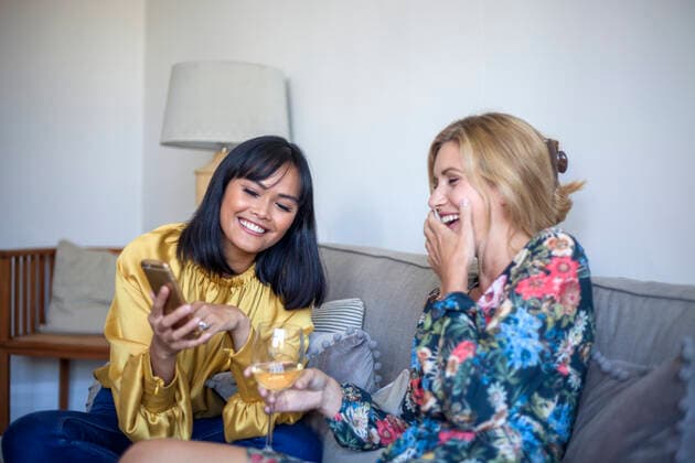 Two friends sitting on couch, chatting, looking at smartphone model released Symbolfoto property released  AJOF00061