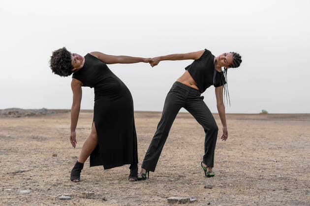 Two women dressed in black performing in bleak landscape model released Symbolfoto  ERRF01930