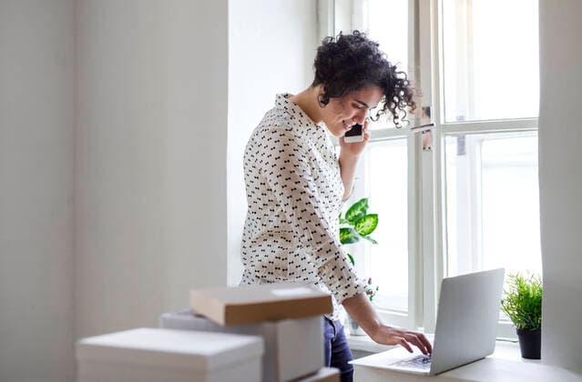 Smiling young woman on the phone using laptop in home office model released Symbolfoto property released  HAPF03087
