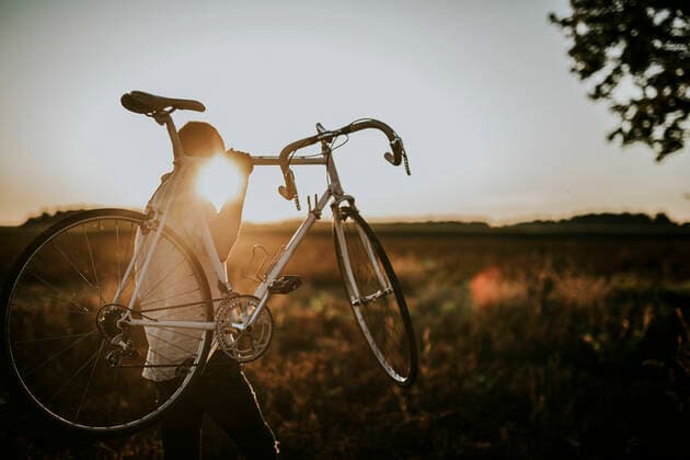 Man carrying a racing cycle in the sunshine model released Symbolfoto  MKF00003