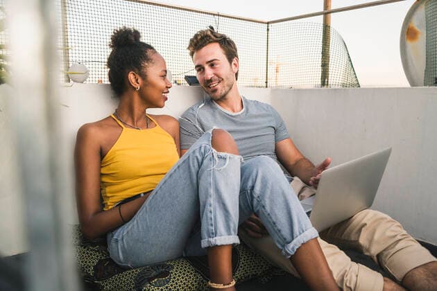 Young couple with laptop and earphones sitting on rooftop in the evening model released Symbolfoto property released  UUF19490