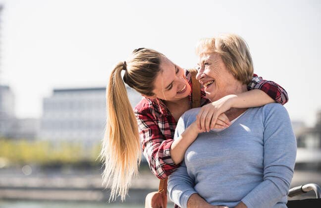 Young woman embracing her smiling grandmother sitting in wheelchair model released Symbolfoto  UUF19542