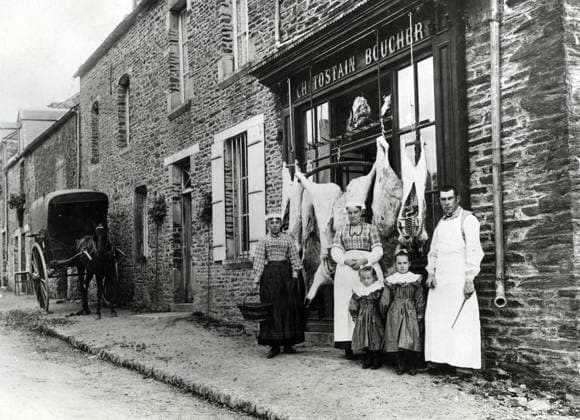 BOUCHERIE Devanture d une boucherie dans un petit village francais, Charles TOSTAIN, boucher le pere boucher, deux femmes et deux petites filles avec des robes identiques. Les femmes portent la BONNETTE , coiffe de BAYEUX. Photographie vers 1900. Credit : Collection NBL KHARBINE-TAPABOR. *** Butchers shop in front of a butchers shop in a small French village, Charles TOSTAIN, butcher the butchers father, two women and two little girls with identical dresses Women wear the BONNETTE, BAYEUX hat Photography around 1900 Credit Collection NBL KHARBINE TAPABOR  KH151327