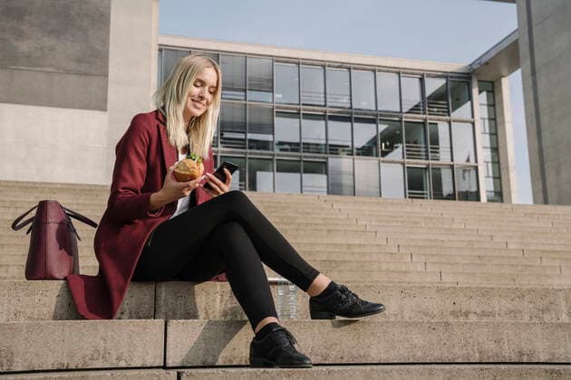 Blond businesswoman having a lunch outside and using smartphone model released Symbolfoto  AHSF01370