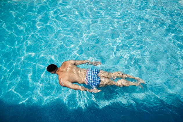 Back view of man floating in swimming pool model released Symbolfoto  MIMFF00003