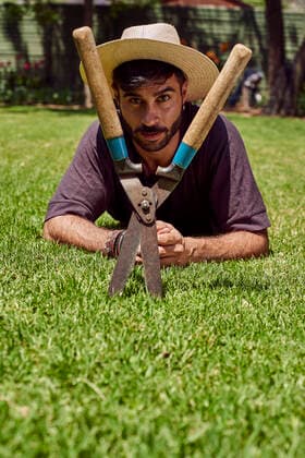 Portrait of man with pruner lying on lawn in garden model released Symbolfoto  VEGF00888