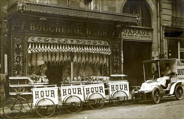 BOUCHERIE annees 1900 Deux hommes dans une automobile devant une boucherie, avec des carcasses d animaux suspendues. Boucherie HOUR , triporteurs devant pour livraisons. Photographie anonyme pour une carte postale vers 1906. Credit : Collection IM KHARBINE-TAPABOR *** Butcher shop 1900s Two men in a car in front of a butcher shop, with animal carcasses hanging Boucherie HOUR , delivery trolleys in front for deliveries Anonymous photograph for a postcard around 1906 Credit Collection IM KHARBINE TAPABOR  KH179080