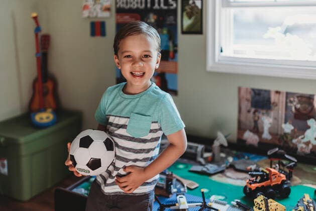 IMAGO Creative: Jahreszeit Winter, Fantasievoll drinnen spielen Smiling 5 yr old holding soccer ball in bedroom with LEGO play table La Mesa, CA ,editorial use only CR_KESM191114A-213173-01