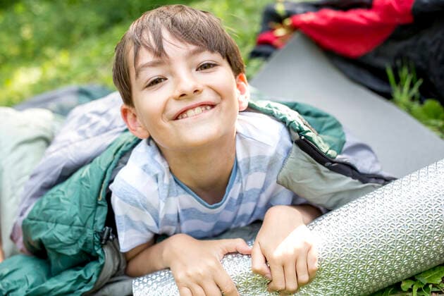 Little boy lying on sleeping bag, looking at camera model released Symbolfoto  WESTF24489