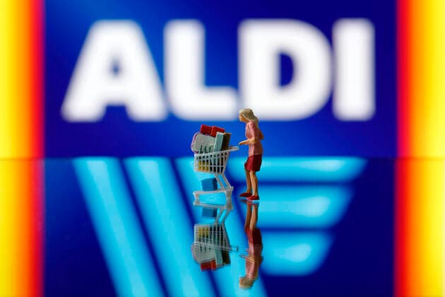 A woman pushes a shopping trolley in front of the logo of the Aldi Group Foto:xC.xHardtx xFuturexImage