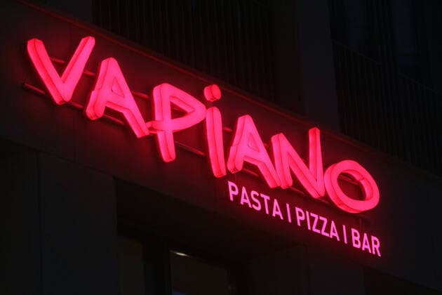 leuchtender Schriftzug Vapiano an der Fassade einer Filiale in Köln am Abend, Nordrhein Westfalen, Deutschland *** illuminated lettering Vapiano on the facade of a branch in Cologne in the evening, North Rhine-Westphalia, Germany