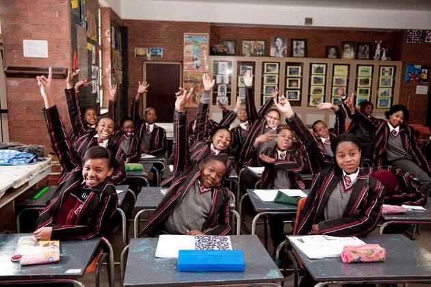 An overall view of a class full of students raising their hands  Copyright: xGreatstockx PE-204-0043G