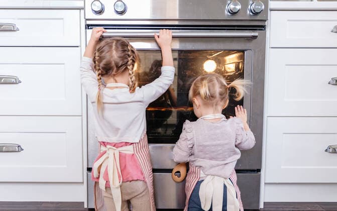 Toddlers looking into oven at baking cookies Courtenay, BC, Canada CR_EMYE191211E-250059-01