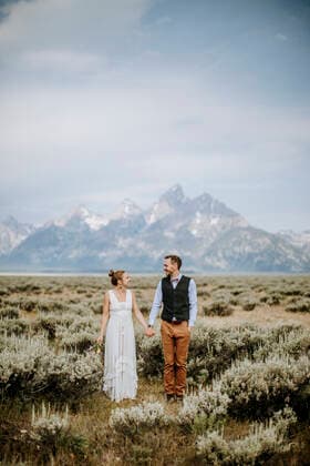 Happy smiling newlywed bride and groom stand in front of Grand Teton Jackson, WY, United States CR_SSNF200106C-254115-01