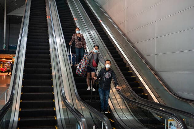 31 01 2020, Singapore, Republic of Singapore, Asia Air travellers arriving on an escalator on their way to the underground station at Changi Airport They wear respiratory masks to protect themselves against infection with the corona virus