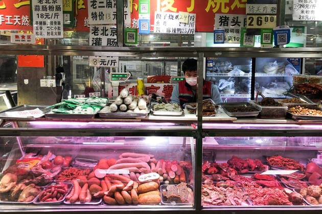 BEIJING, CHINA - FEBRUARY 17, 2020: A vendor in a face masks selling meat products at Shengfu Xiaoguan Market. Zoya Rusinova TASS  TS0CEA52