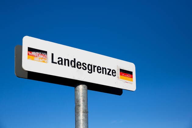 sign border Germany in front of blue sky 1083401727