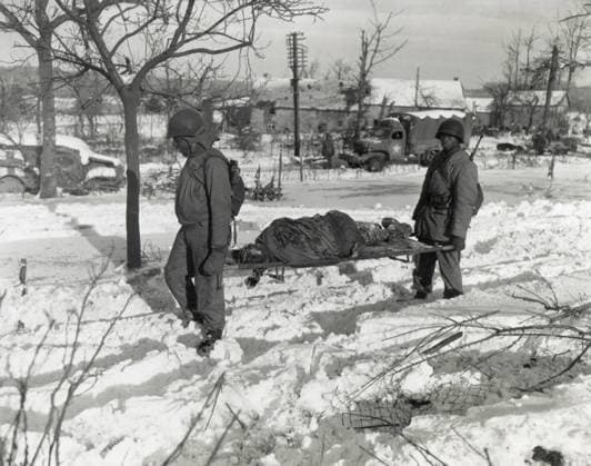 Two African American soldiers carry the body of an soldier on a stretcher during World War 2. Dead soldier is one of the victims of the German Waffen-SS massacre of 80 American POWs in Belgium, during the Battle of the Bulge, Dec. 1944. African Americans Courtesy Everett Collection PUBLICATIONXNOTxINxCANxCHNxFRAxITAxJPNxNORxPOLxRUSxESPxUKxUSA Copyright: xCourtesyxEverettxCollectionx HISL036 EC928