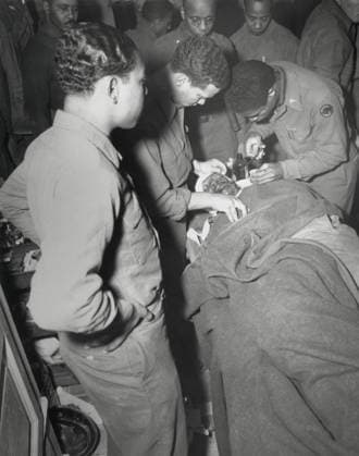 African American Army surgeon stitches face and shoulder wounds in the Pietrasanta Area, Italy. Feb. 10, 1945. Capt. Ezekia Smith, 370th Inf. Regt., 92nd Div. was wounded by shell fragments near Querceta, Italy, during World War 2. (BSLOC_2013_14_235) Courtesy Everett Collection PUBLICATIONXNOTxINxCANxCHNxFRAxITAxJPNxNORxPOLxRUSxESPxUKxUSA Copyright: xCourtesyxEverettxCollectionx HISL036 EC933