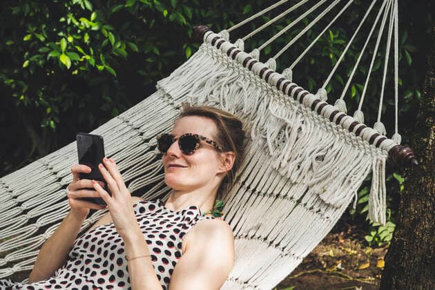 Smiling woman lying in a hammock using cell phone model released Symbolfoto  CHPF00602