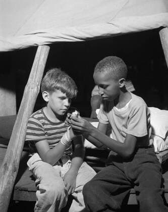 African American camper helps a White bubby with his bandaged hand. They are at Camp Nathan Hale, Southfields, NY, which was supported by the Methodist Camp Service in Aug. 1943 photo by Gordon Parks. (BSLOC_2014_13_102) For usage credit please use; PUBLICATIONXNOTxINxCANxCHNxFRAxITAxJPNxNORxPOLxRUSxESPxUKxUSA Copyright: xCourtesyxEverettxCollectionx HISL038 EC348