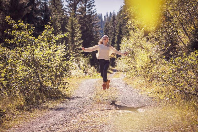 Girl running and jumping on a forest path, having fun model released Symbolfoto  DHEF00118