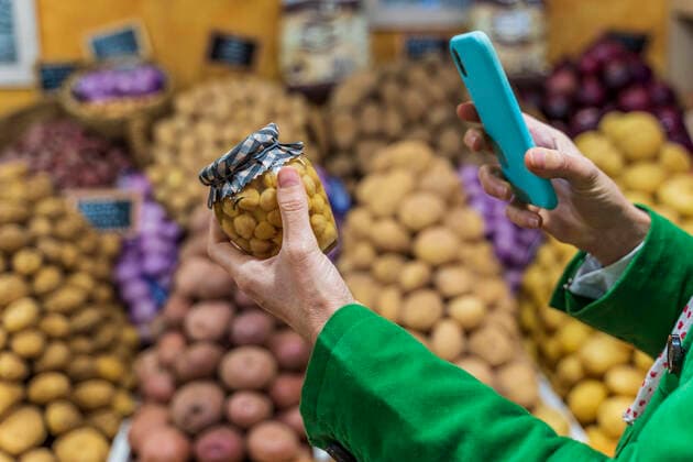 Woman using smartphone app to check a preserving jar model released Symbolfoto property released  DLTSF00534