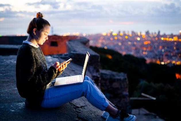Young woman sitting on railing above the city using cell phone, Barcelona, Spain model released Symbolfoto  GIOF07945