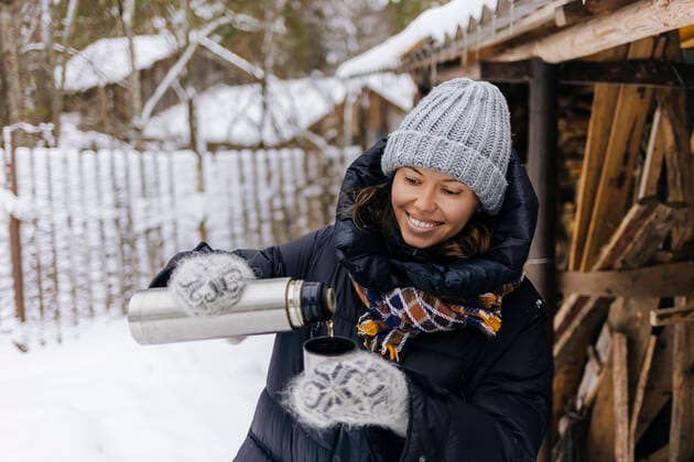 Portrait of happy woman using thermo flask in winter model released Symbolfoto  KNTF04215