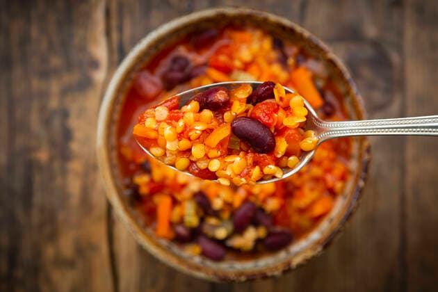 Spoon of vegan chili with red lentils, celery sticks, kidney beans, tomatoes and carrots  LVF08574