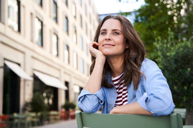 Portrait of smiling brunette woman sitting on a chair in the city model released Symbolfoto  PNEF02235