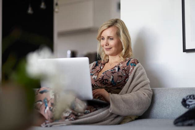 Blond woman using laptop on couch at home model released Symbolfoto property released  RBF07058