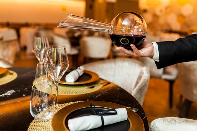 Waiter pouring wine from decanter into glass in fancy restaurant model released Symbolfoto property released  VABF02574