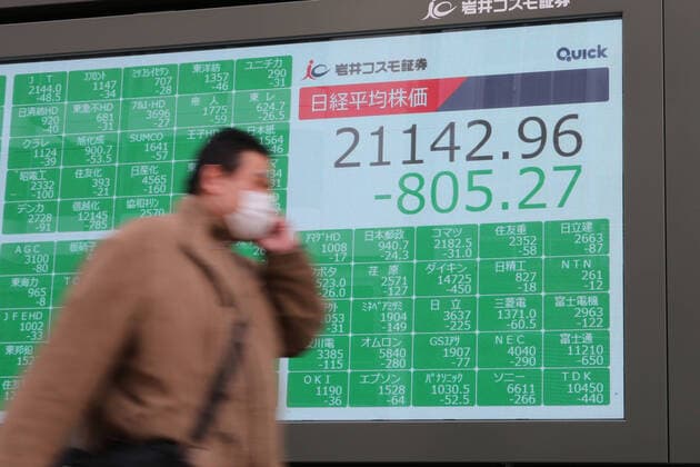 A man wearing a face mask walks past an electronic stock board showing Japan s Nikkei Stock Average in Tokyo, Japan on February 28, 2020. The Nikkei Stock Average closed 3.67 percent lower at 21,142.96, for the fears of the global economic impact on the coronavirus outbreak.  (123329855)