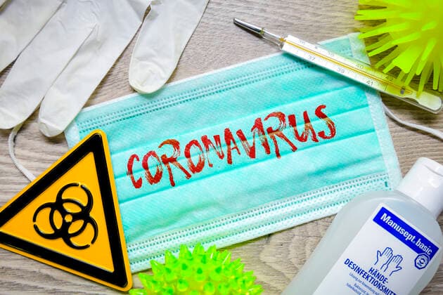 PHOTOMONAY, mouthguard with Coronavirus lettering, biohazard shield, protective gloves, clinical thermometer and disinfectant on a table ** NUR FUER REDAKTIONELLE ZWECKE ** EDITORIAL USE ONLY **