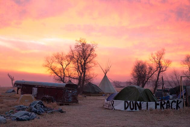 IMAGO Nature: Unsere Erde, Umweltverträgliche Herausforderungen, Fracking A tipi and an anti-fossil fuels slogan are seen during a fiery sunrise over the opposition camp against the Dakota Access oil pipeline on November 14, 2016, North Dakota, United States. CANNON BALL North Dakota UNITED STATES Copyright: xTerrayxSylvesterx STANDINGROCK_TER_0052
