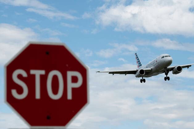 (200312) -- WASHINGTON D.C., March 12, 2020 -- Photo taken on March 10, 2020 shows a stop sign and a plane approaching to land at Ronald Reagan Washington National Airport in Arlington, Virginia, the United States. U.S. President Donald Trump said on Wednesday night the country will suspend all travel from European countries except Britain for 30 days in a bid to fight the ongoing coronavirus outbreak. ) U.S.-NOVEL CORONAVIRUS-OUTBREAK-TRAVEL SUSPENSION LiuxJie 