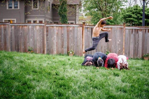 A strong shirtless boy with defined muscles leaps over stack of people Columbus, OH, United States ,model released, Symbolfoto CR_RETI200120B-250656-01