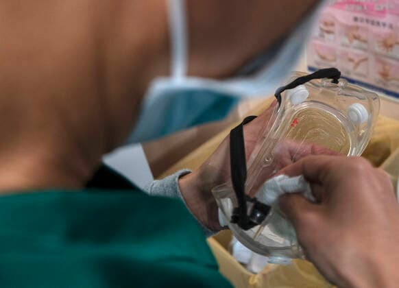 Coronavirus in China, Eindrücke aus Wuhan (200314) -- WUHAN, March 14, 2020 -- Team member Wu Hongkun cleans a goggle in Wuhan, central China s Hubei Province, March 13, 2020. Amid the coronavirus outbreak, many transferring teams fight at the frontline. Exposed to the danger of infection, they shuttle between hospitals and medical treatment stations around the clock to make sure that patients are transported to designated places in time. Nine members from Yunnan Province, namely Liu Jianyong, Huang Jie, Yang Hui, Yao Hongjun, Wu Hongkun, Liu Mengdi, He Xueping, Pang Qingli and Yue Dingkun, made up a transferring team and went to Wuhan, the epicenter of the epidemic, on Feb. 19 to contribute to the battle against the novel coronavirus there. By 23:00 of March 13, the team has transferred a total of 2,753 patients, including 129 people in critical condition and 245 with severe sy
