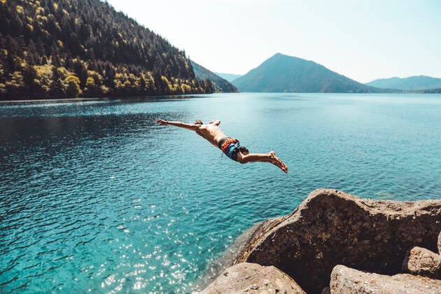 IMAGO Creative: Ende des Sommers Side view of young male jumping in alpine lake in front of mountains Port Angeles, WA, United States ,model released, Symbolfoto CR_MAKO200206D-304979-01