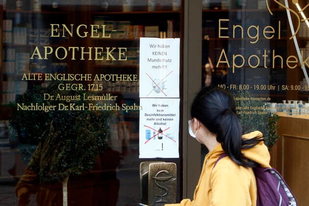 A tourist from Asia passes a pharmacy in downtown Munich with a breathing mask, which cannot offer disinfectants, breathing masks or alcohol because it is sold out, Munich, Bavaria, Germany