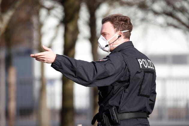 18 03 2020, Fairgrounds, Hall 13, Hanover, Laatzen, checkpoint for suspected corona cases, in the picture policeman with protective mask signals Corona Drive In