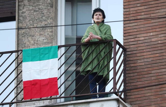 foto ipp giorgio rossi milano 20 03 2020 emergenza coronavirus - radio per l italia: tutte le emittenti nazionali hanno suonato in contemporanea l inno nazionale nella foto una signora canta l inno affacciata al balcone di casa con una bandiera dell italia  0