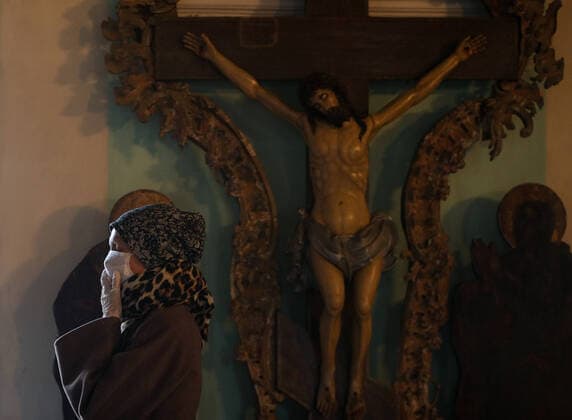 MOSCOW, RUSSIA - MARCH 20, 2020: A believer in a medical mask during an evening service at the Vysokopetrovsky Monastery. Starting from March 18, monks conduct a religious procession and spray holy water after the evening service at the monastery amid the coronavirus pandemic. Sergei Bobylev TASS  TS0D2EE8