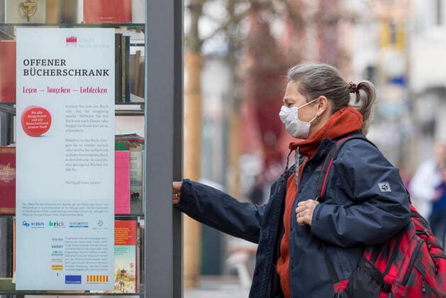 Wuerzburg, City 20 03 2020, Coronavirus Borrow books in times Coronas picture A woman stands on Friday in front of an open bookcase in downtown Wuerzburg Because of the corona crisis, she has a protective mask on Bavaria, coronavirus, COVID 19, Germany, Franconia, disaster, consumption, diseases, Mainfranken, protective measures, Wuerzburg, precaution, protection, Copyright: HMBxMediax xPattyxVarasano